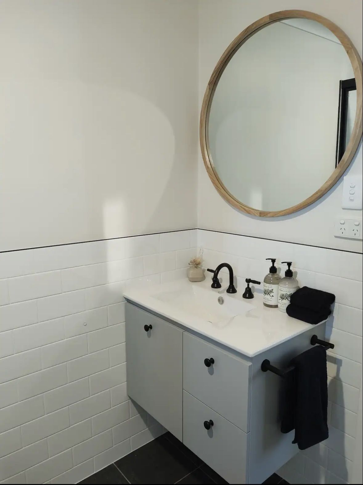 Bathroom with vanity, round mirror and folded towels