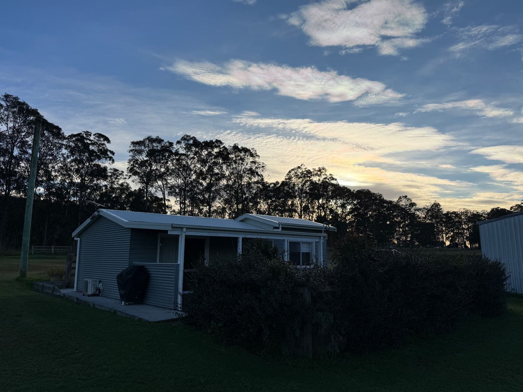 Last light over the tree line and paddocks below the cottage